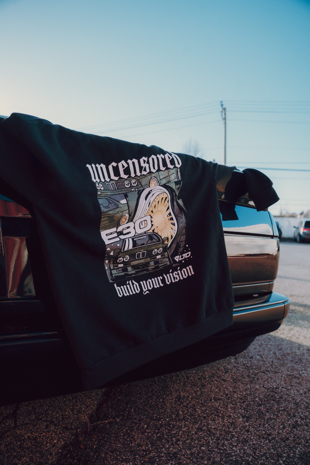 Hoodie Uncensored draped over a vehicle at golden hour
