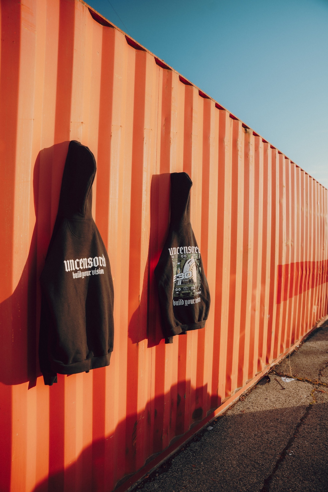 Deux hoodies suspendus sur container orange